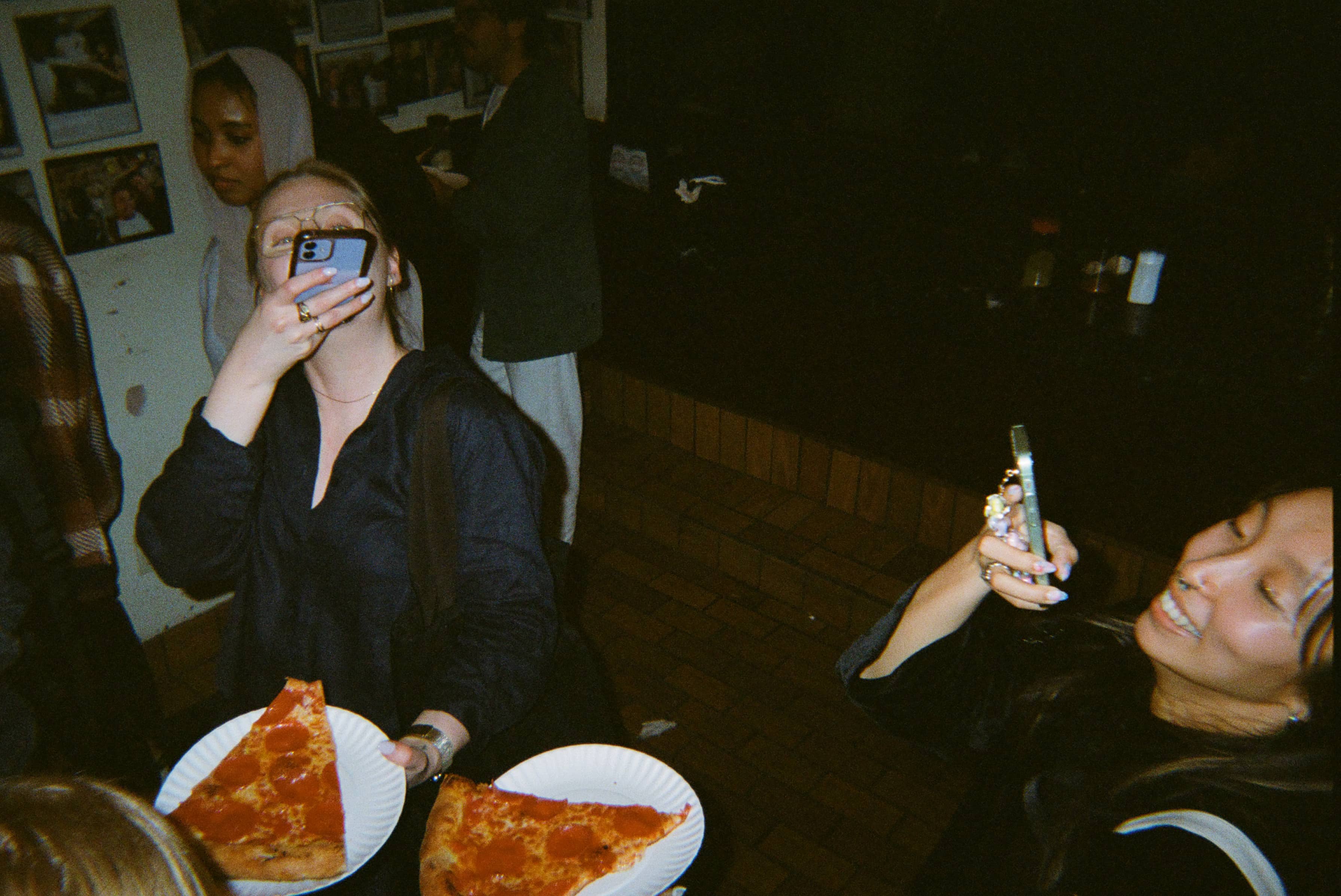 Two women holding plates of pizza.
