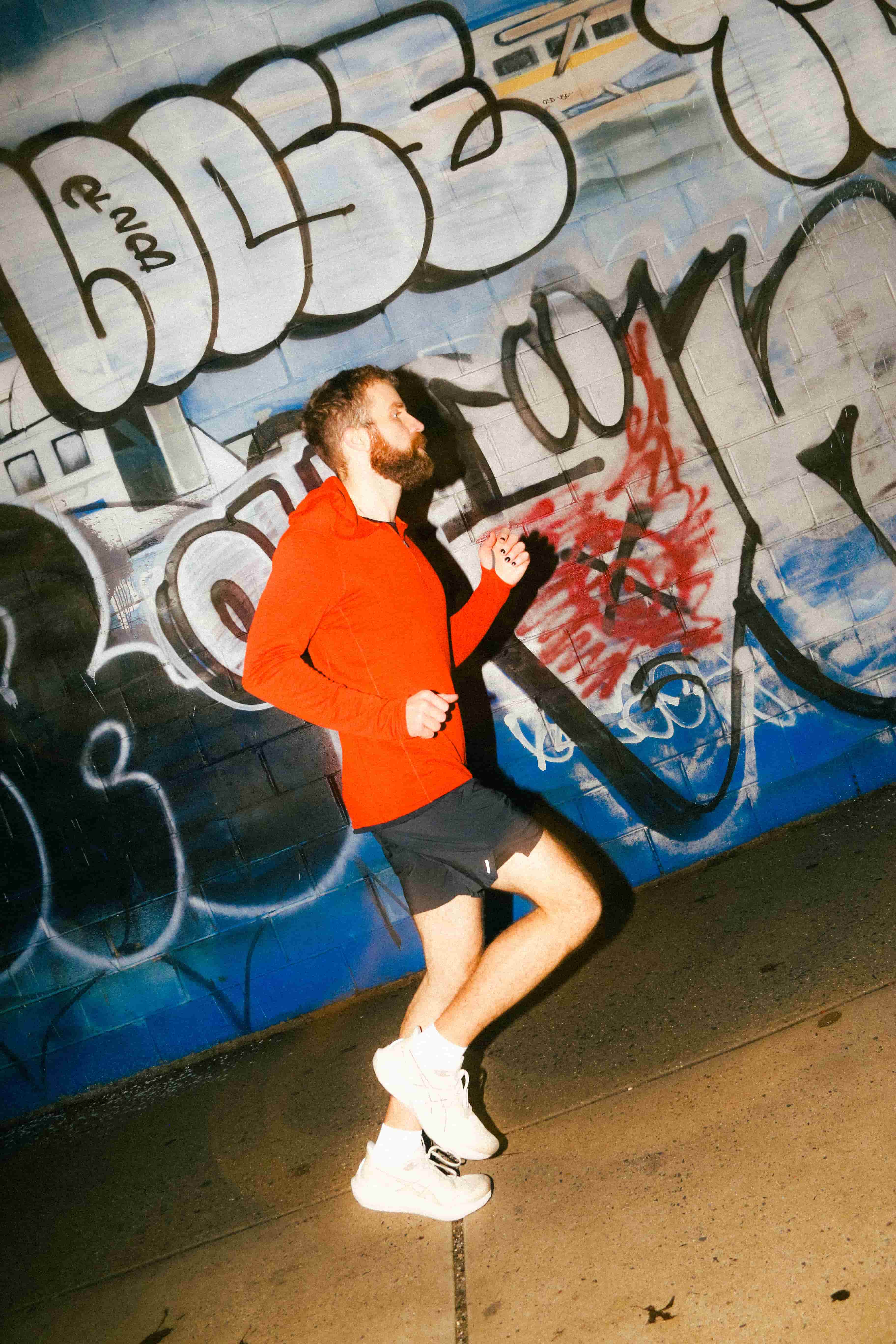 A person running in front of a wall with graffiti.