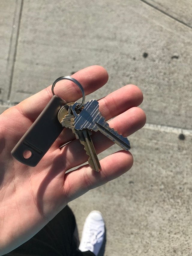 A hand holding two keys on a keyring.