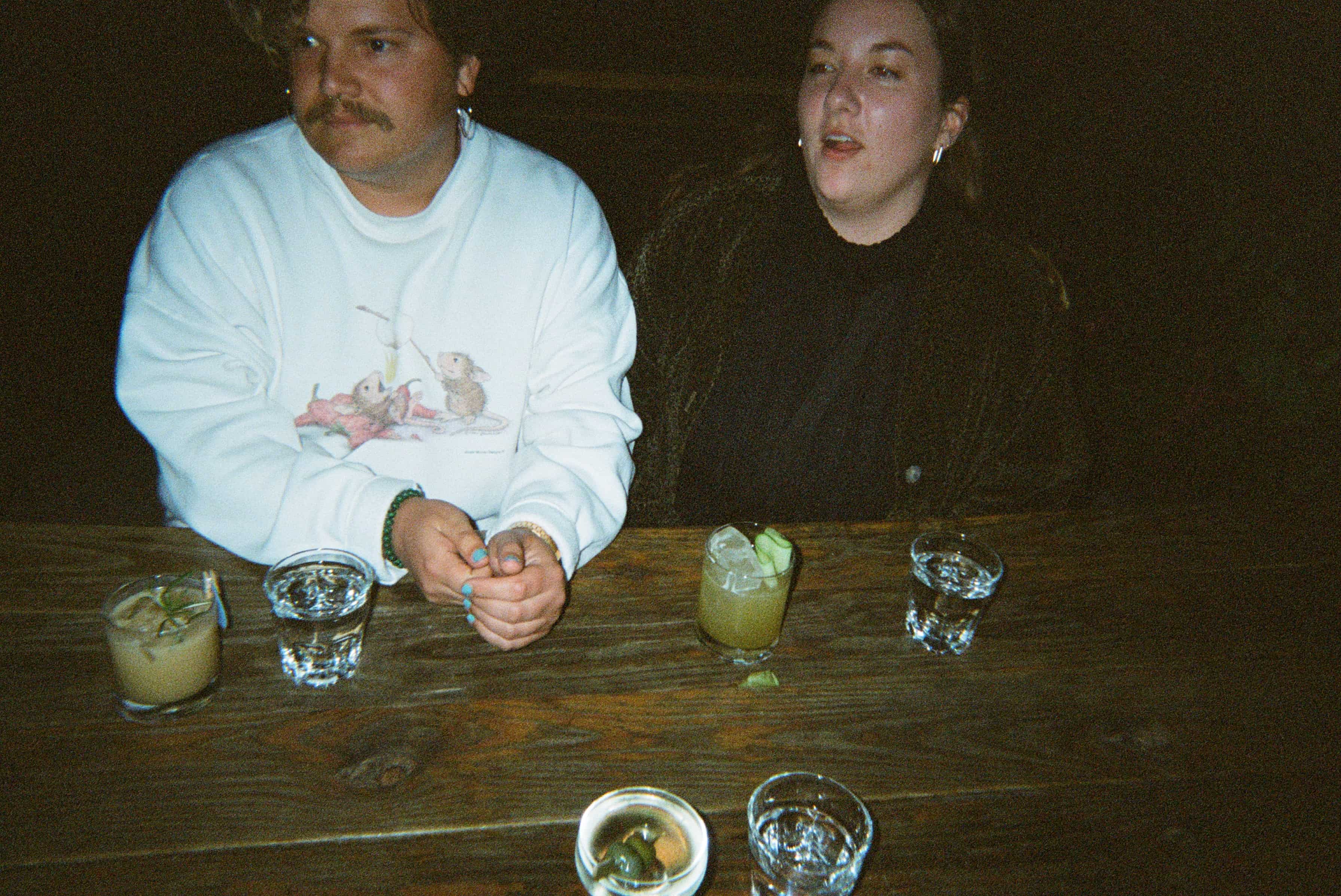 Two peoeple sitting at a table with drinks.