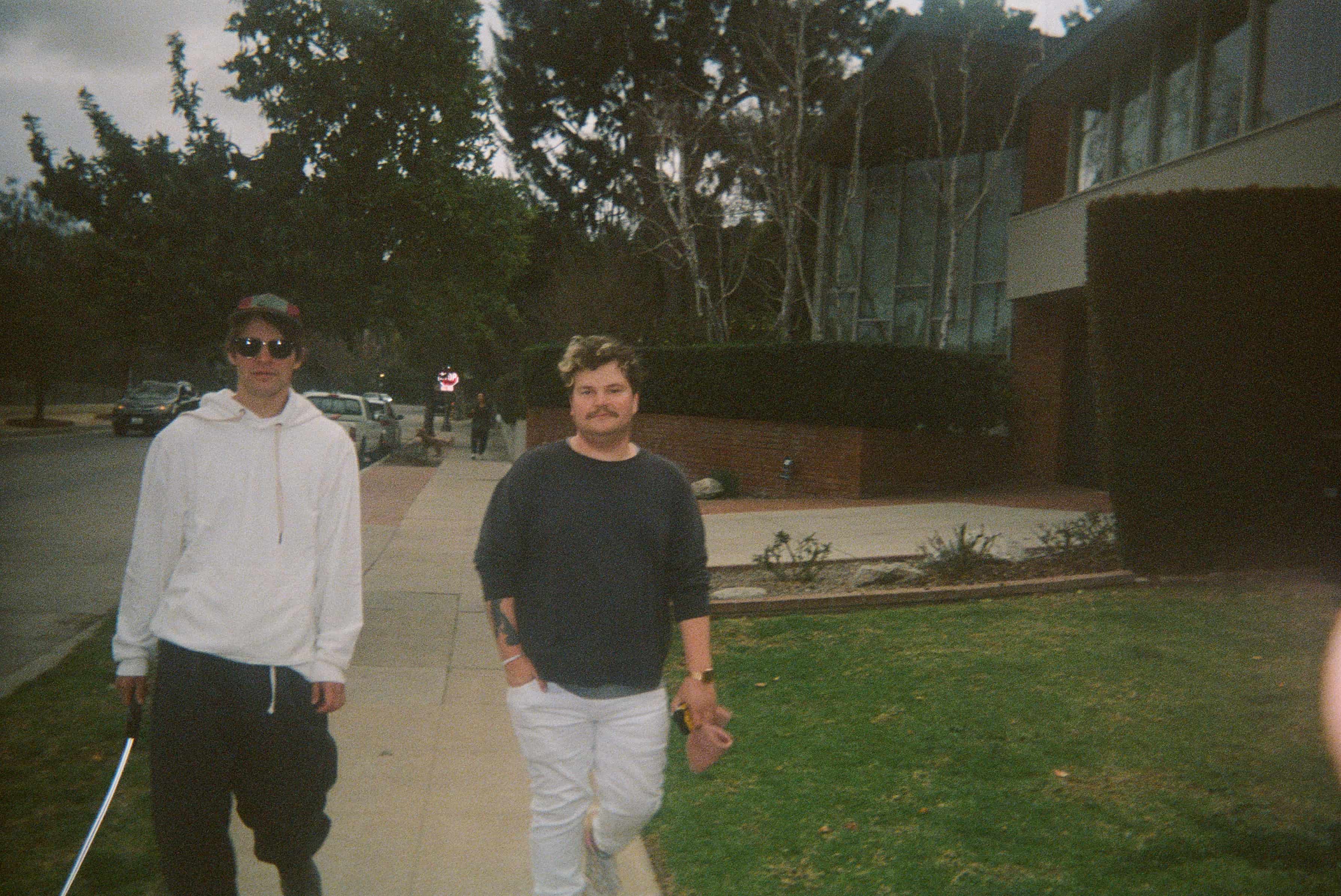 Two people standing on a sidewalk.