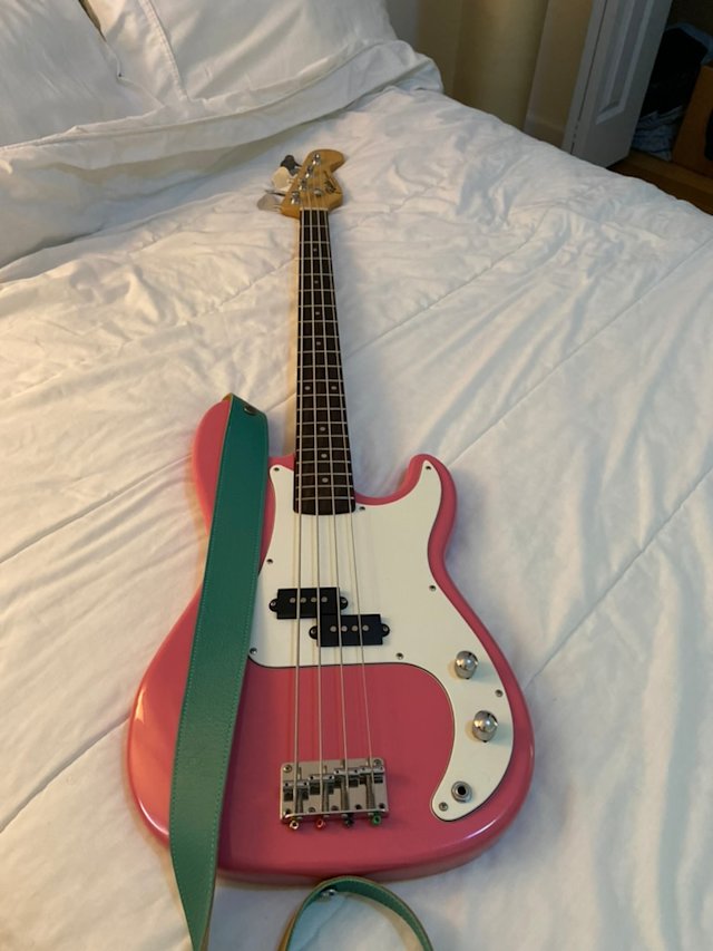 Pink and white electric P-bass with a sea green faux leather strap.