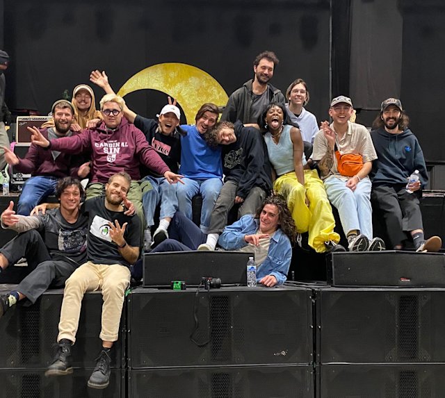 A crowd of people sitting on a stage embracing each other.