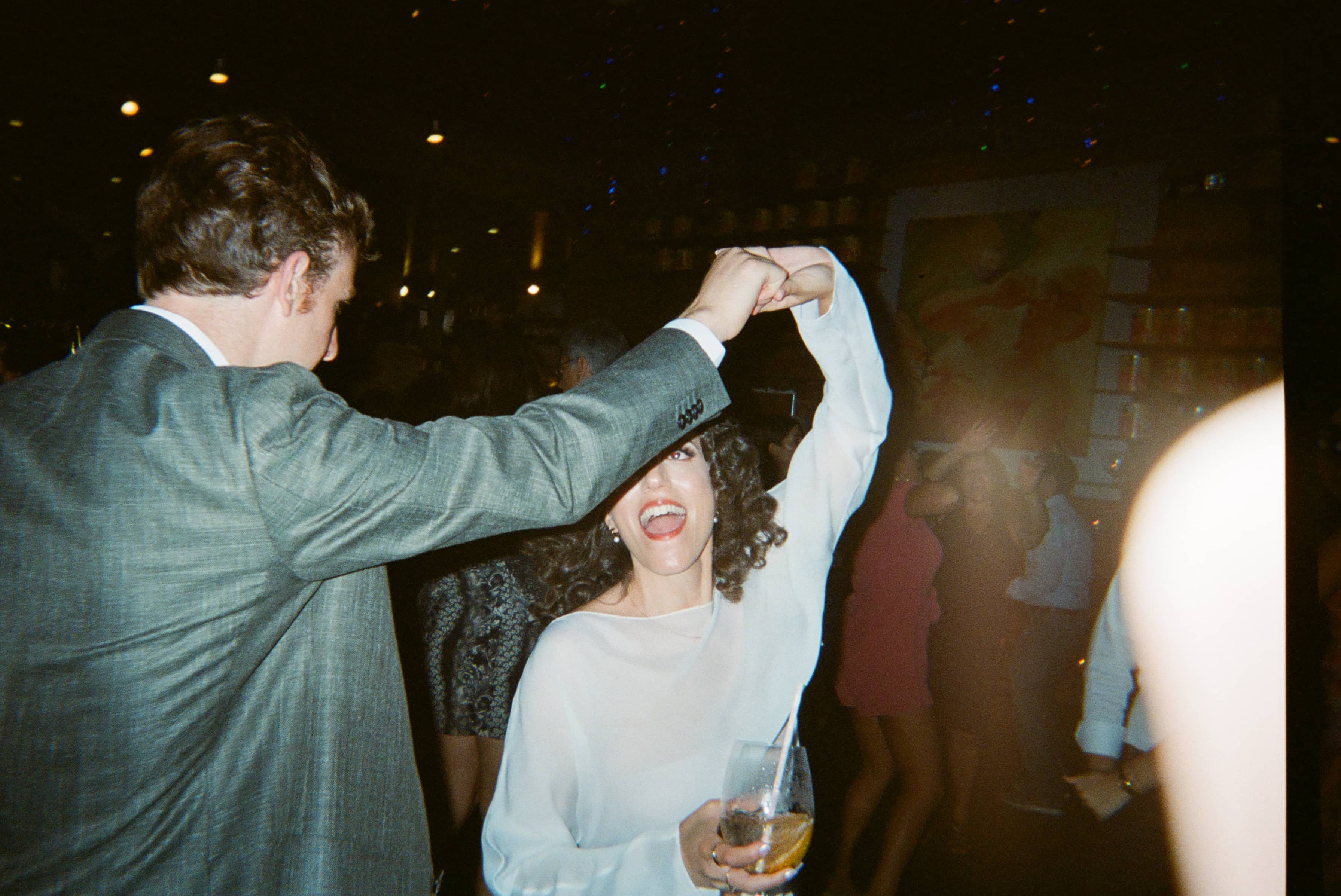 A woman holding a glass of wine dancing with a man.