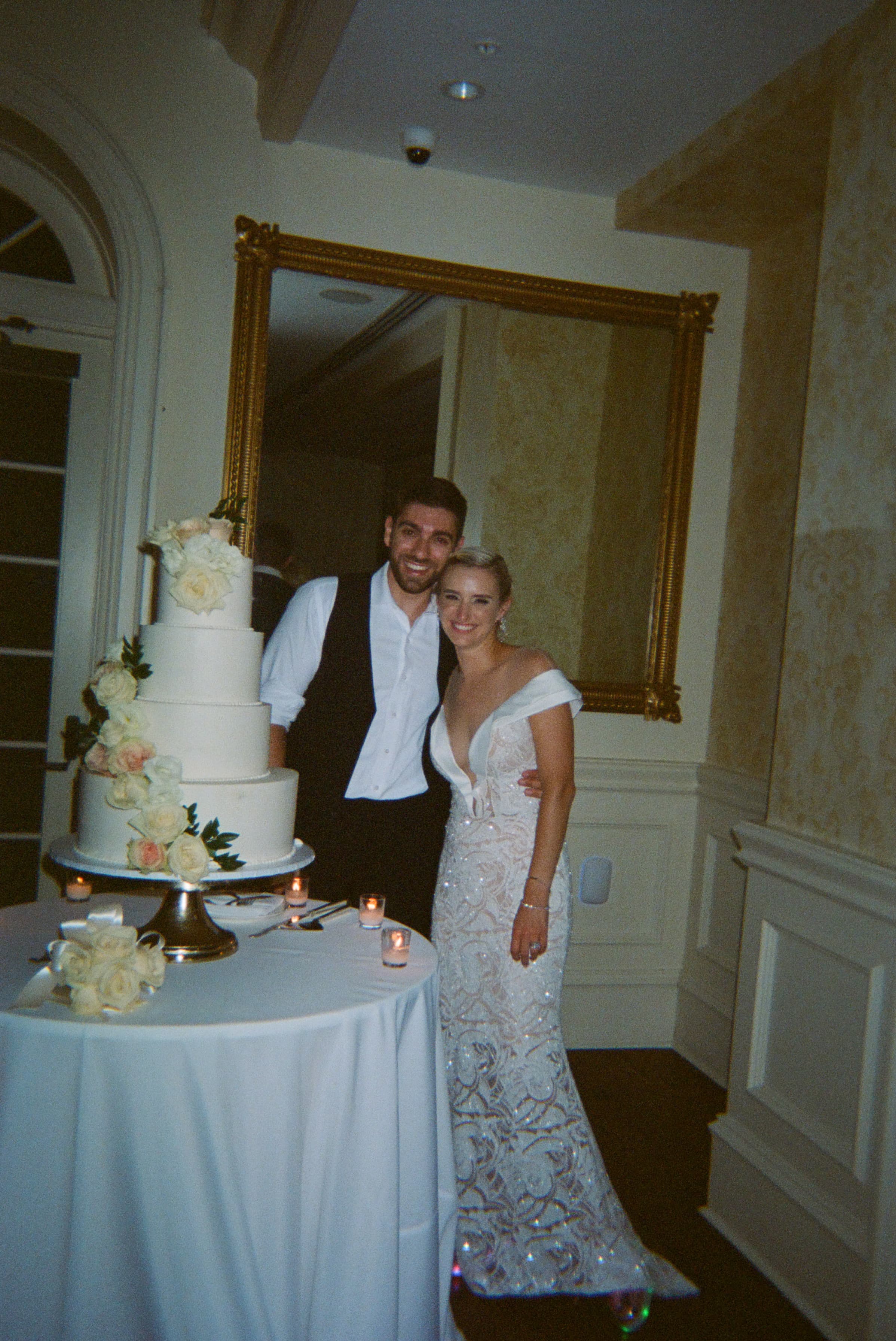 Two people standing next to a wedding cake.