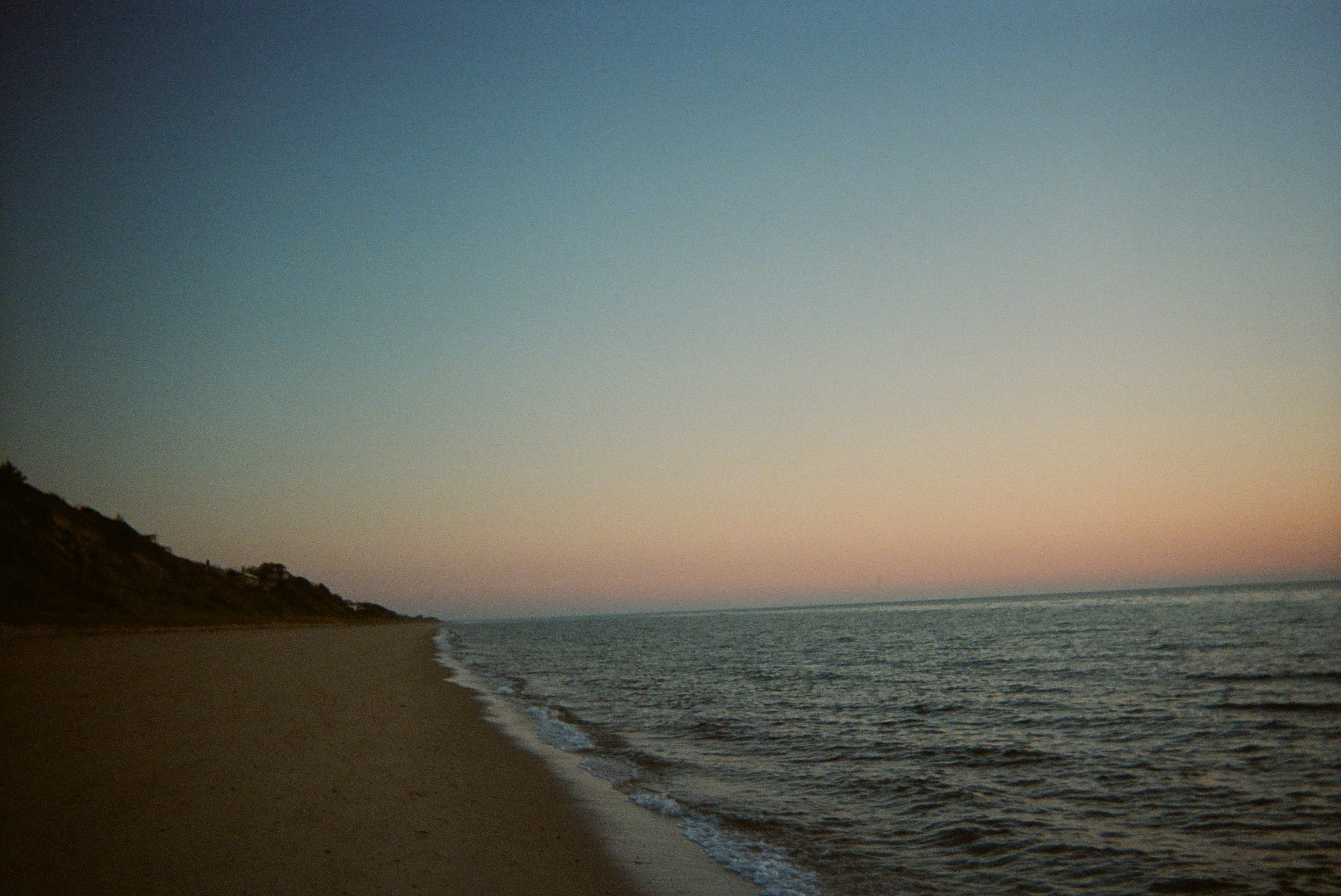 A beach with waves crashing on the shore at dusk.