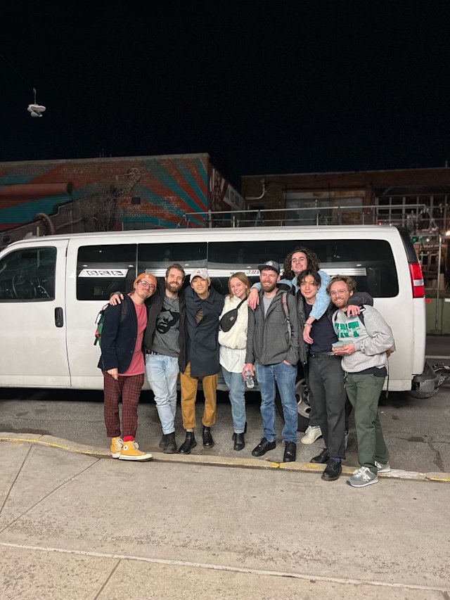 Group of people posing in front of a van.