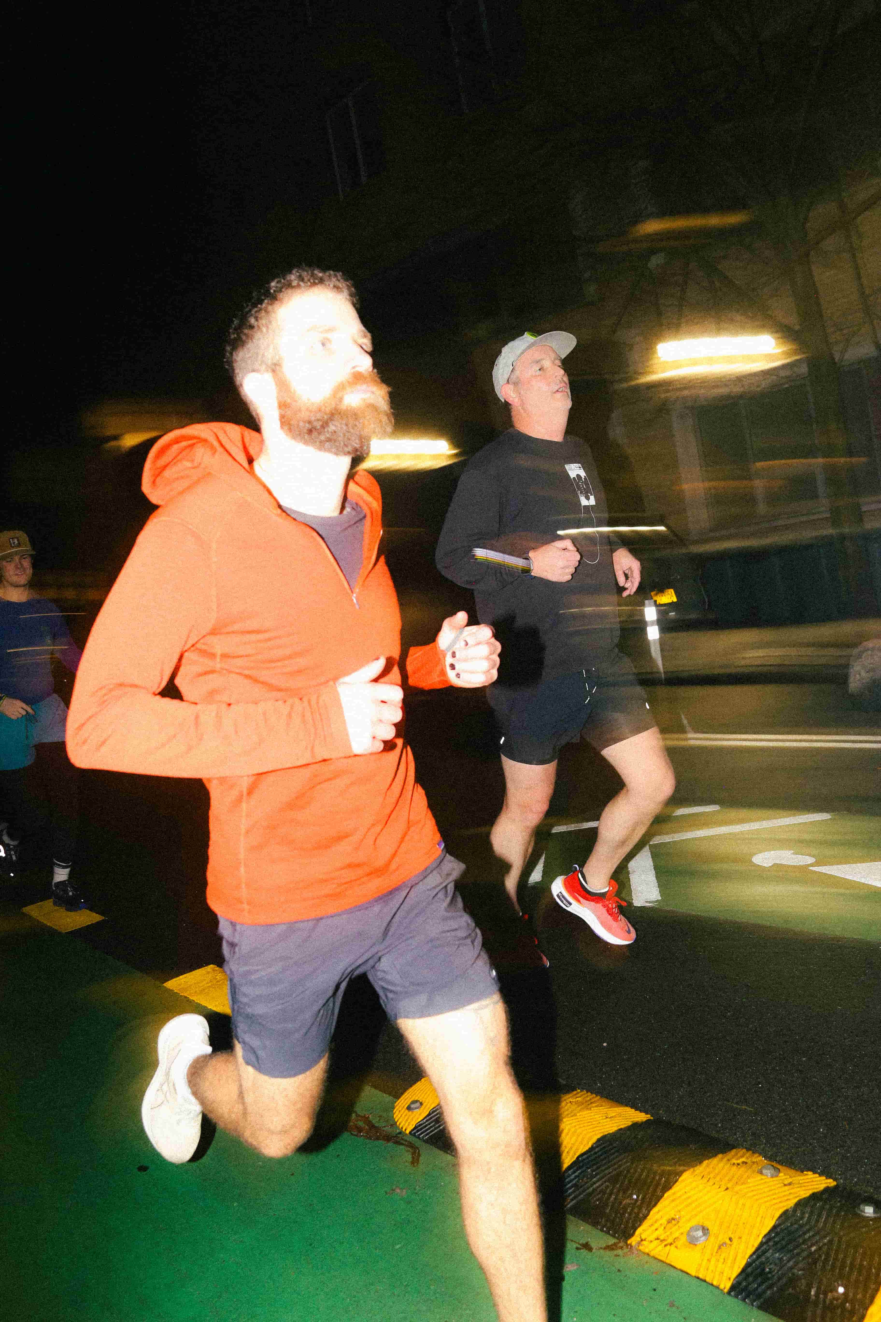 A group of men running on a street at night.