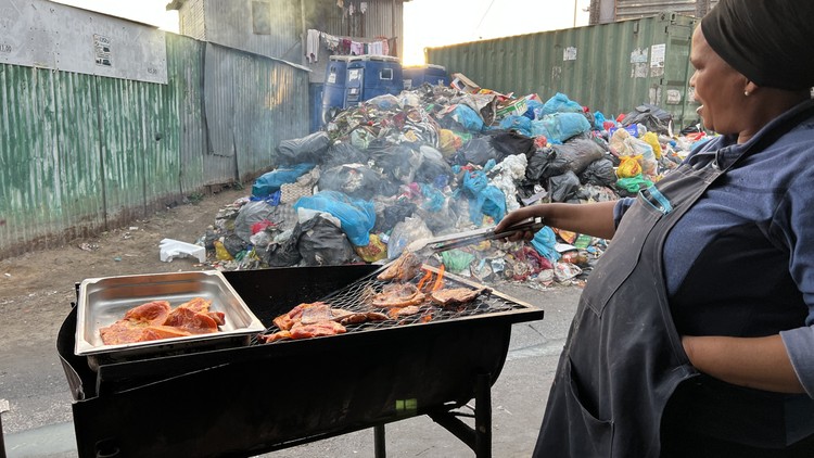 Street vendor Emihle Phoswa braais pork chops and chicken wings near garbage in Dunoon. 
© Peter Luhanga