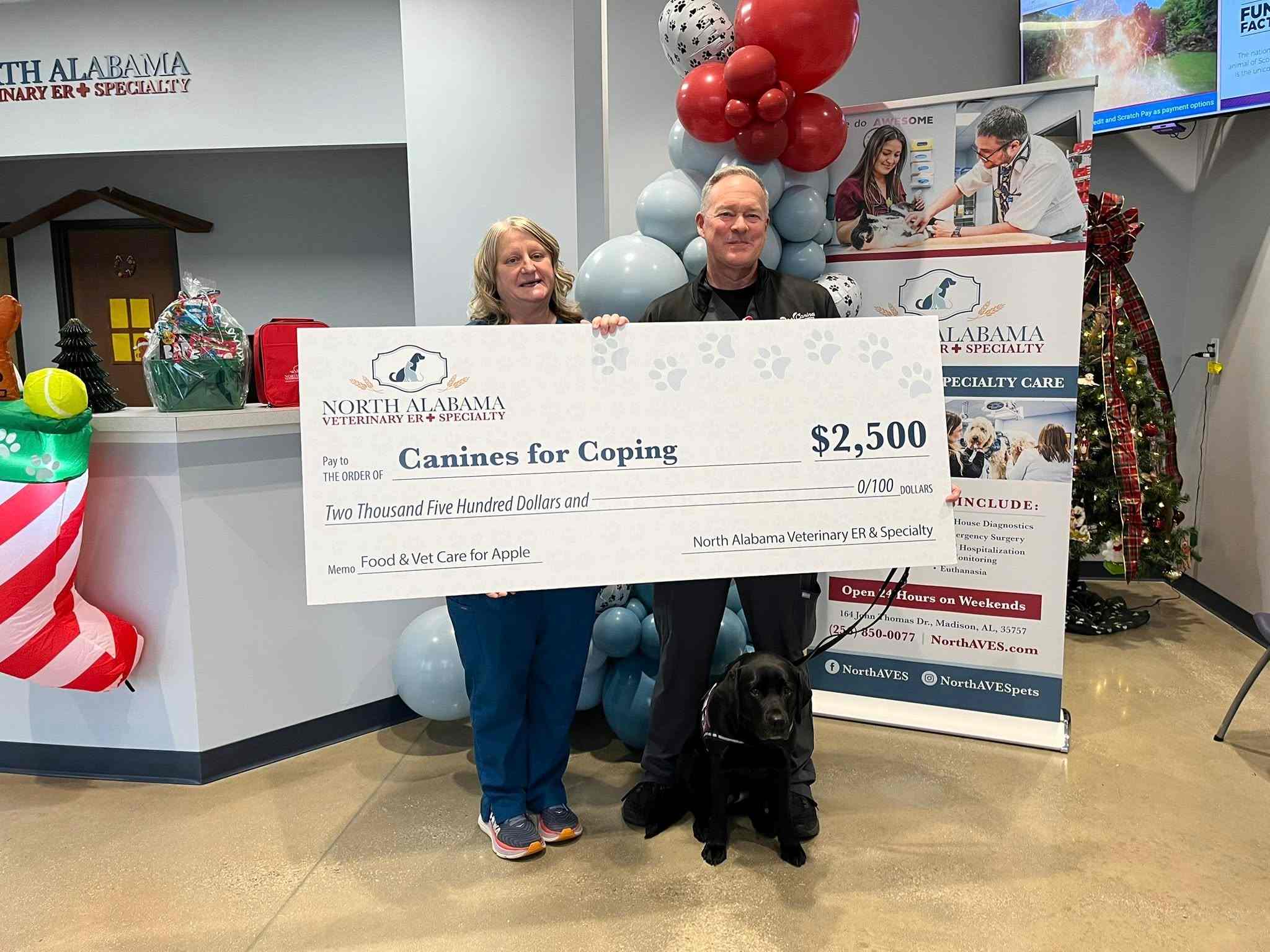 Two people holding a large check in NAVES' front office.