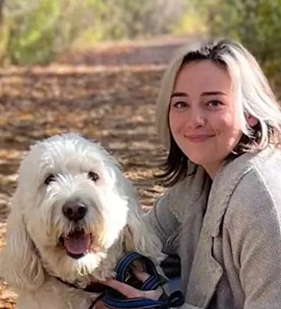 Caitlin posing outdoors with a large fluffy white dog Caitlin posing outdoors with a large fluffy white dog