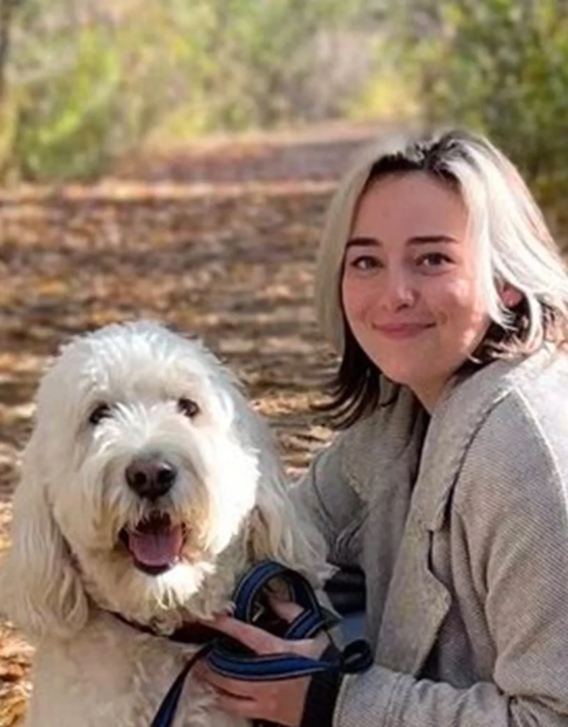 Caitlin posing outdoors with a large fluffy white dog Caitlin posing outdoors with a large fluffy white dog