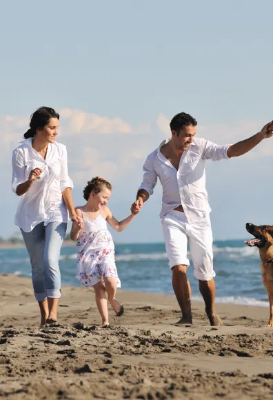 Dog with family running on the beach.