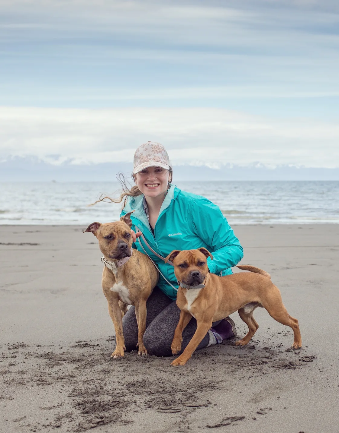 Elora's staff photo from Alaska Veterinary Clinic where she is at a beach with her two brown dogs smiling. Elora's staff photo from Alaska Veterinary Clinic where she is at a beach with her two brown dogs smiling.