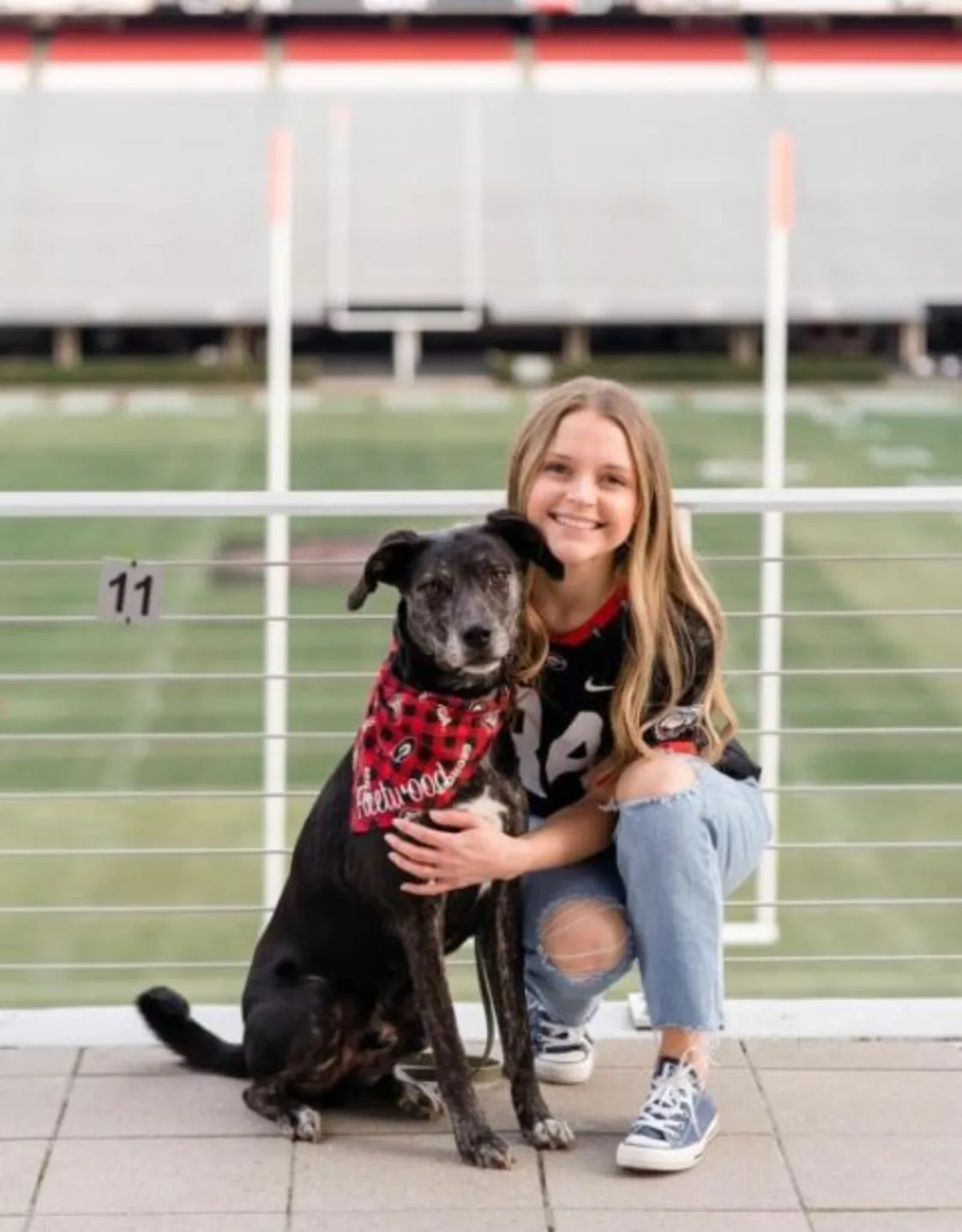 Dr. Justine Gordner holding onto a dog in front of a football field. Dr. Justine Gordner holding onto a dog in front of a football field.