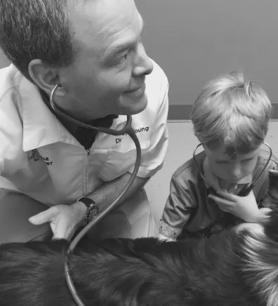 Dr. Troy Young and child using stethoscopes on a dog