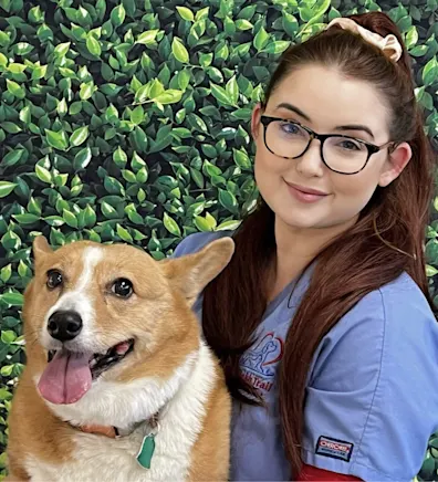 Marina's staff photo from Spanish Trail Animal Hospital where she is outside sitting on a lawn posing for a picture next to tan and white corgi dog. Marina's staff photo from Spanish Trail Animal Hospital where she is outside sitting on a lawn posing for a picture next to tan and white corgi dog.