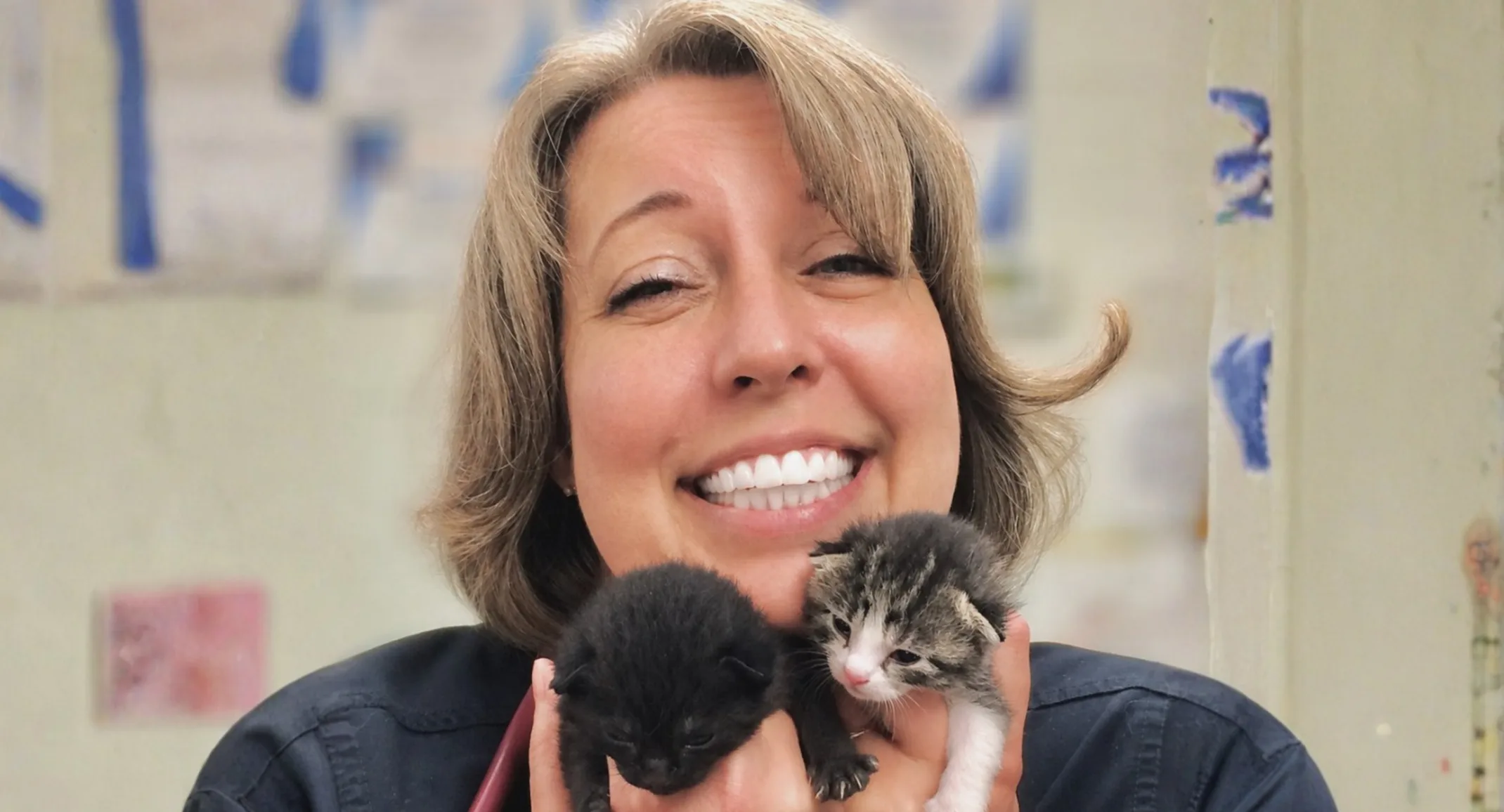 Dr. Mitchell smiling while holding two kittens. Dr. Mitchell smiling while holding two kittens.