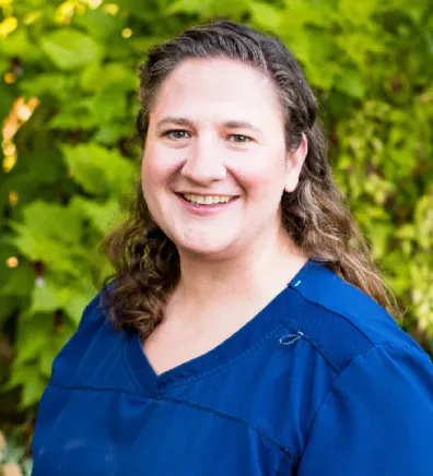 A photo of Dr. Goldman smiling and standing by some greenery