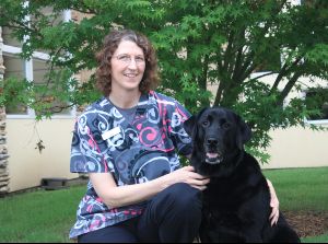 Inger with a black dog at Stuebner Airline Veterinary Hospital