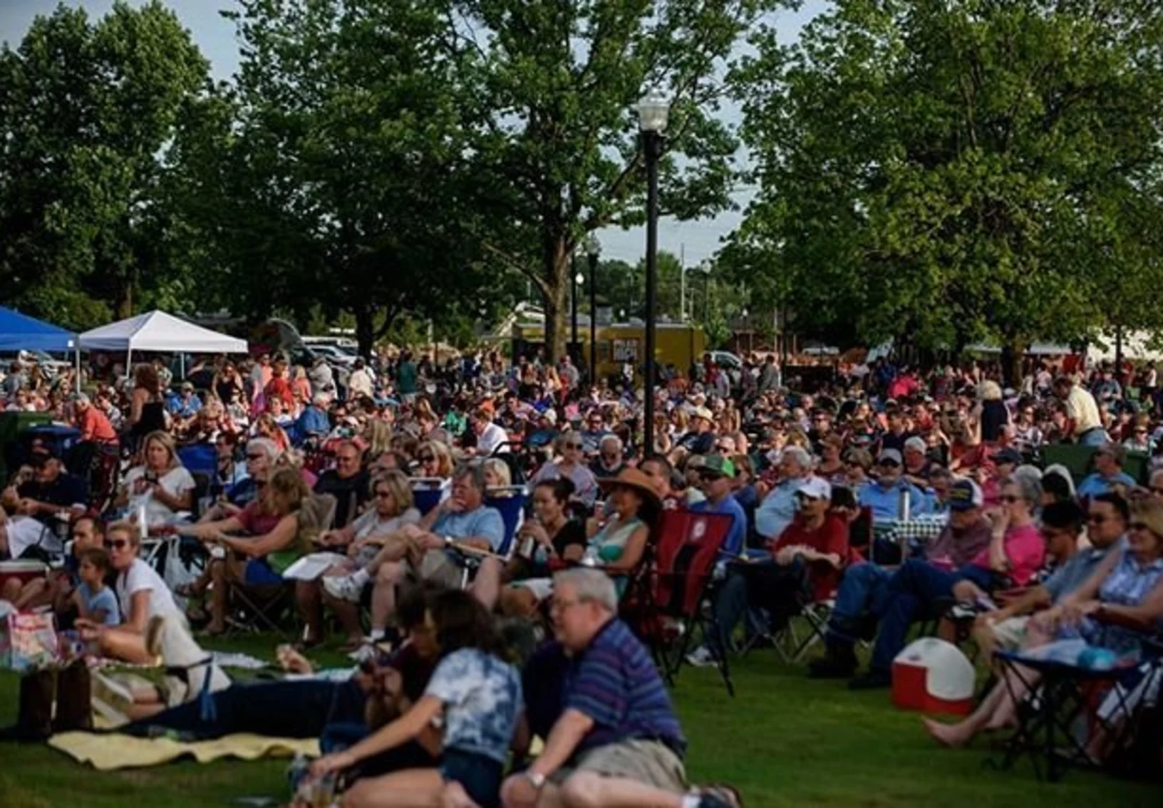 People sitting in a park listening to a concert