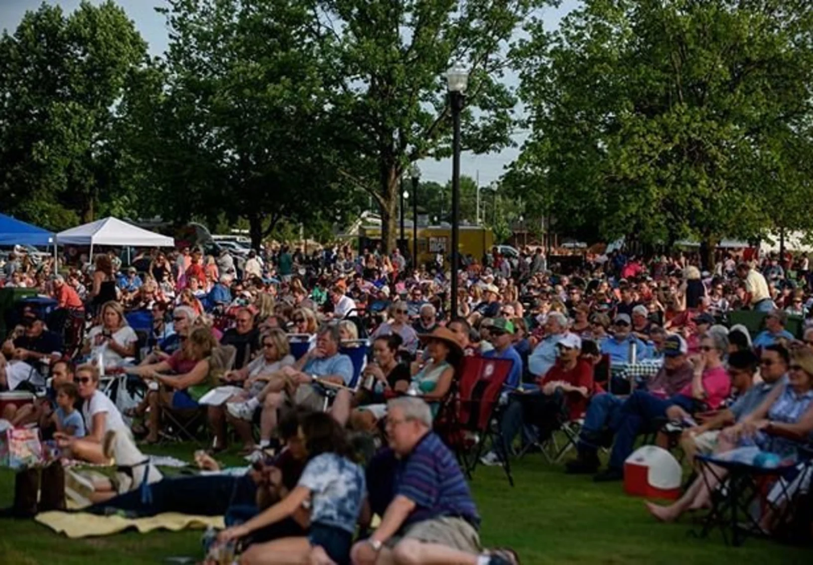 People sitting in a park listening to a concert People sitting in a park listening to a concert