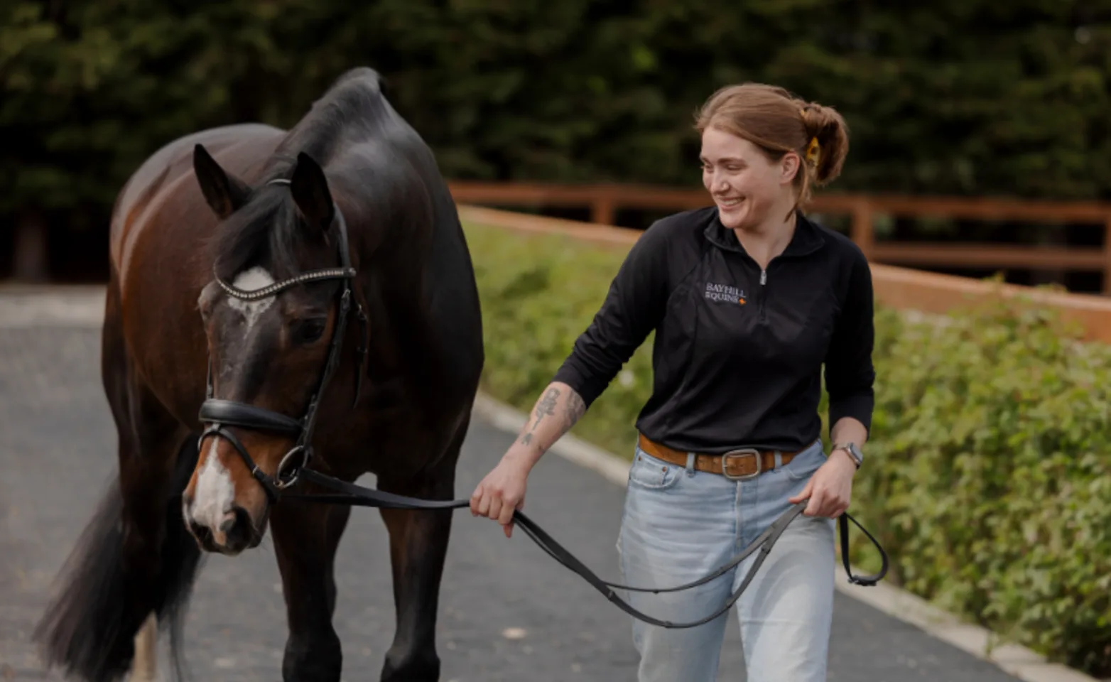 Staff Member Smiling and Guiding a Dark Brown Horse Staff Member Smiling and Guiding a Dark Brown Horse