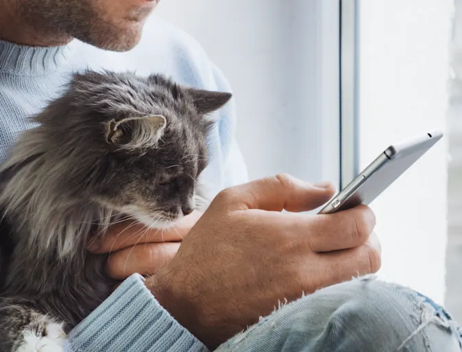 A man holding a phone and his cat A man holding a phone and his cat