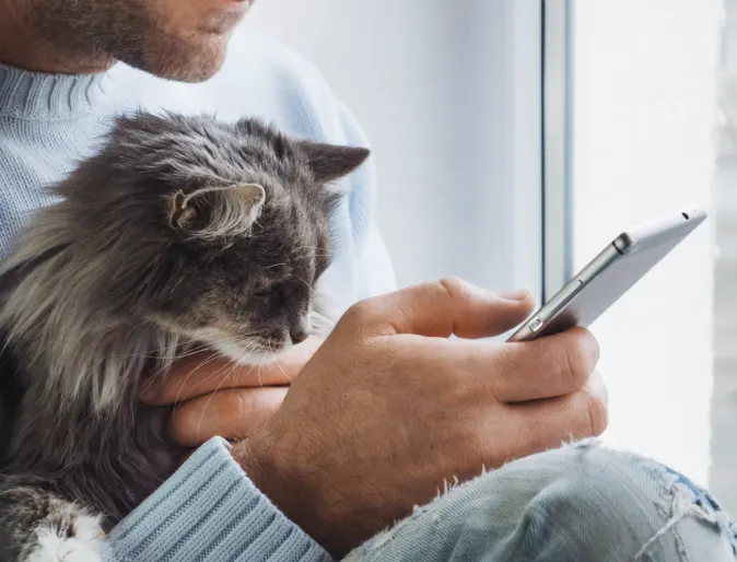 A man holding a phone and his cat