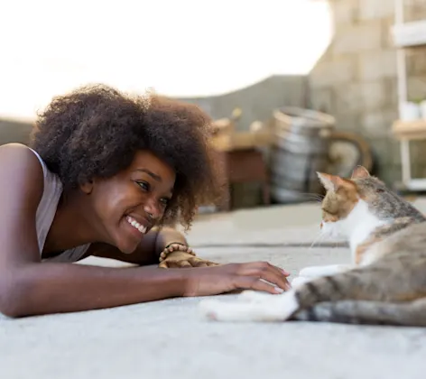 Woman playing with cat on carpet