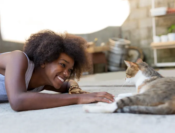 Woman playing with cat on carpet