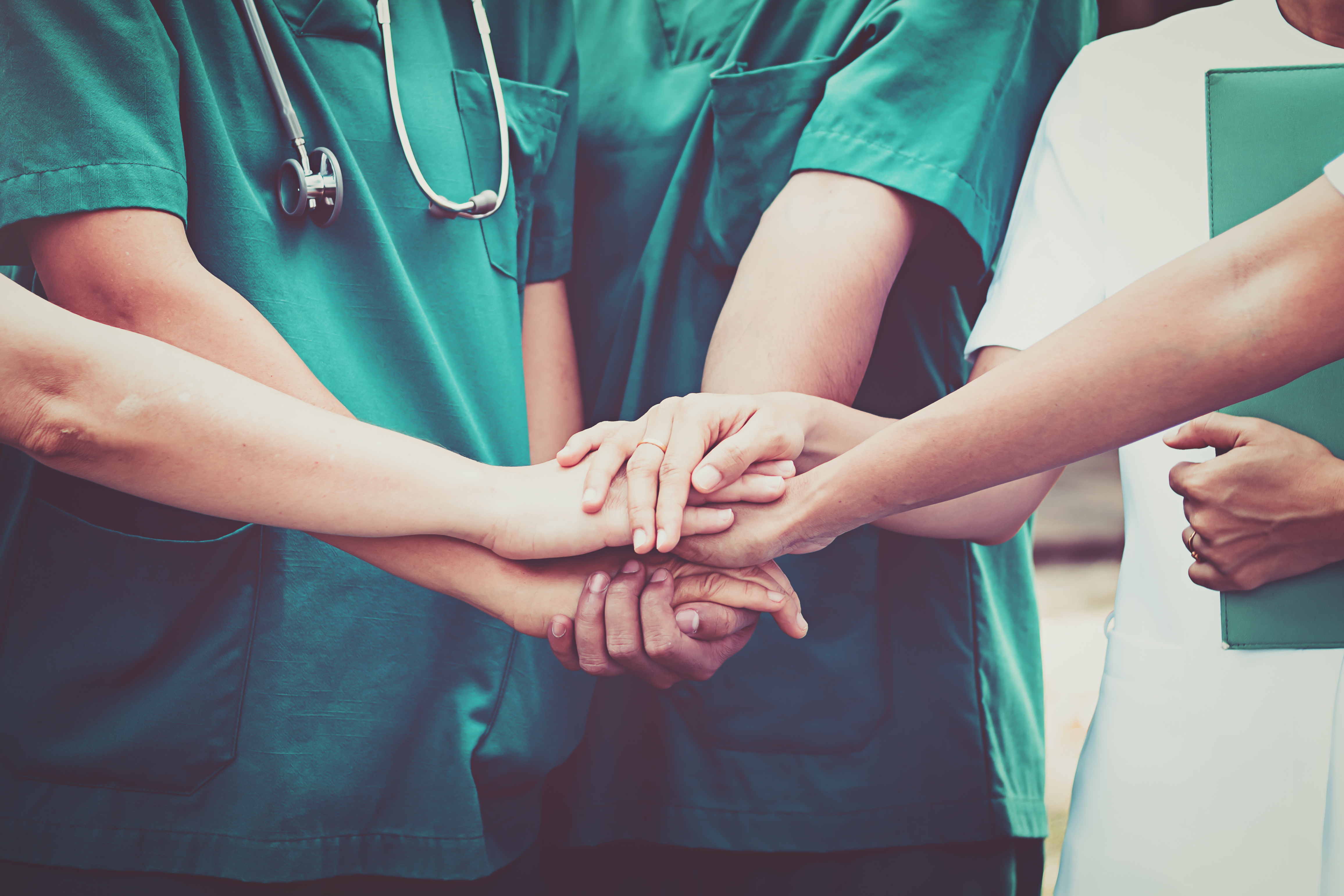 Photo of hospital staff having hands on top of one another to show team work