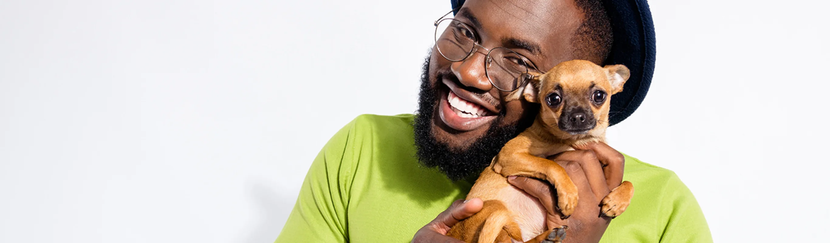 Man wearing green shirt and hat holding a puppy to his face