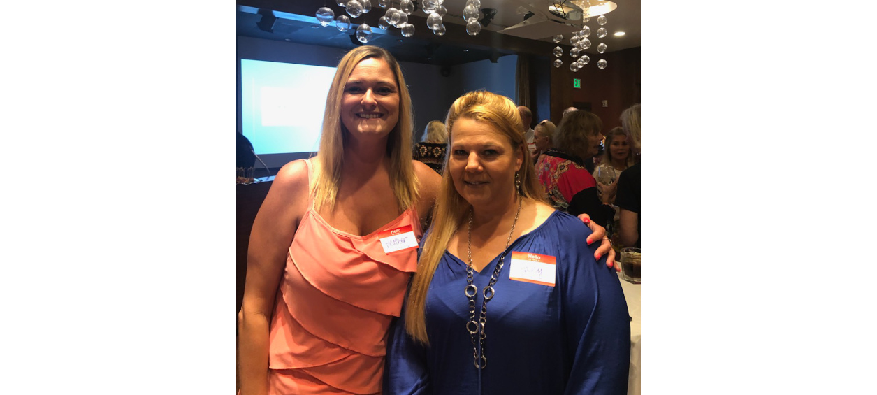 Two blonde women smiling.
