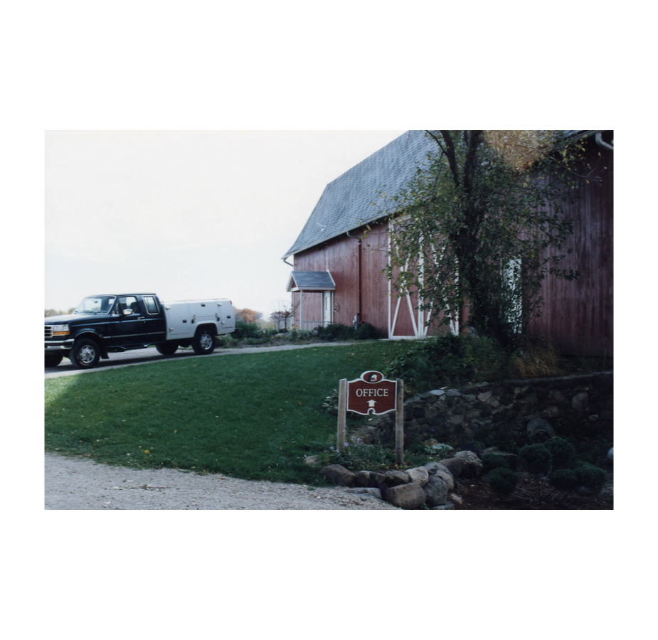 An older photo of WECH's red barn with a Ford pickup truck outside