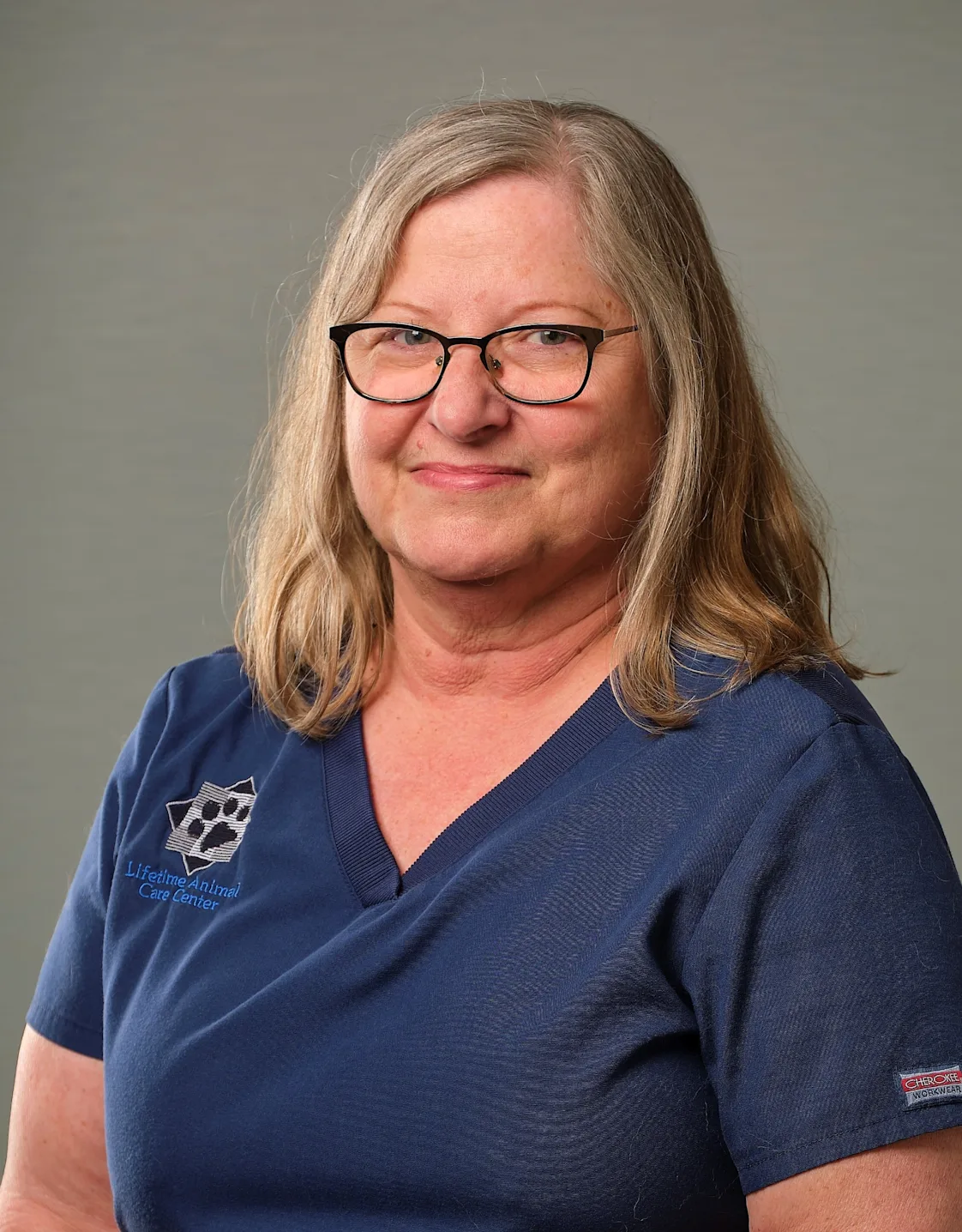 Sue's staff photo from Lifetime Animal Care Center where she is holding a puppy with a graduating cap on its head. Sue's staff photo from Lifetime Animal Care Center where she is holding a puppy with a graduating cap on its head.