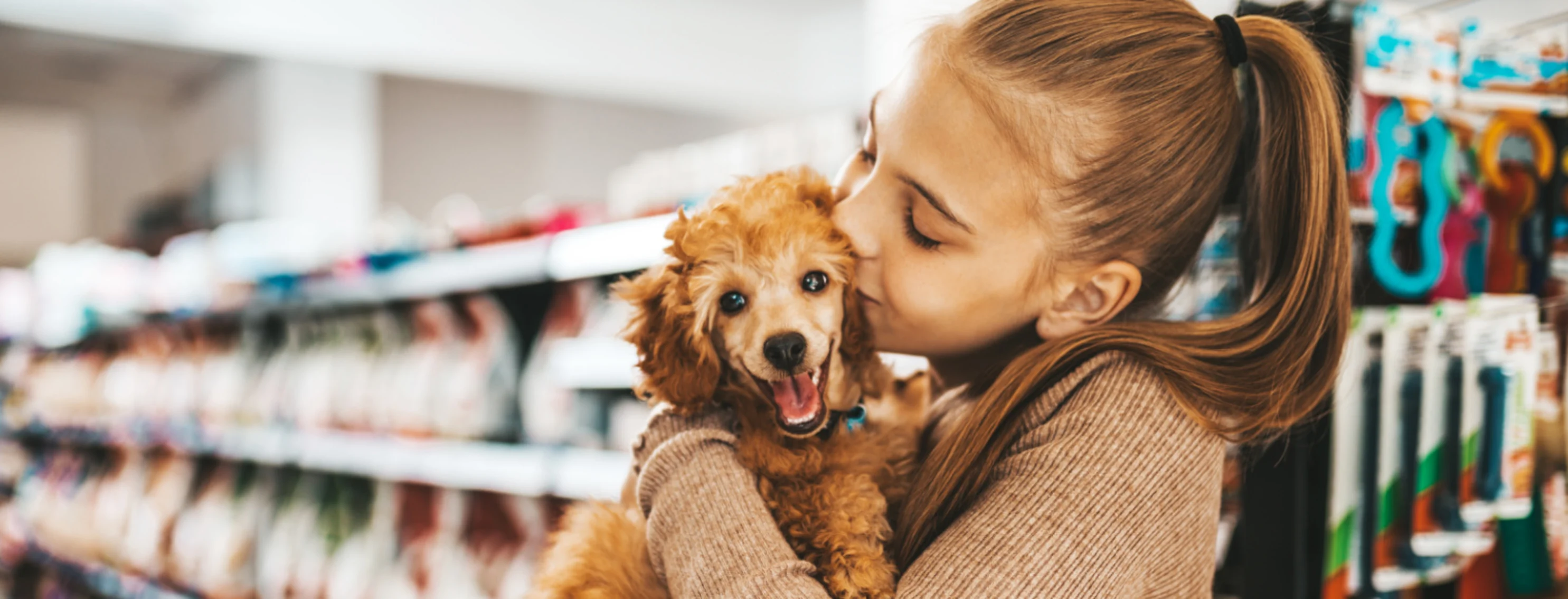 Woman holding dog in store with food shelves behind Woman holding dog in store with food shelves behind
