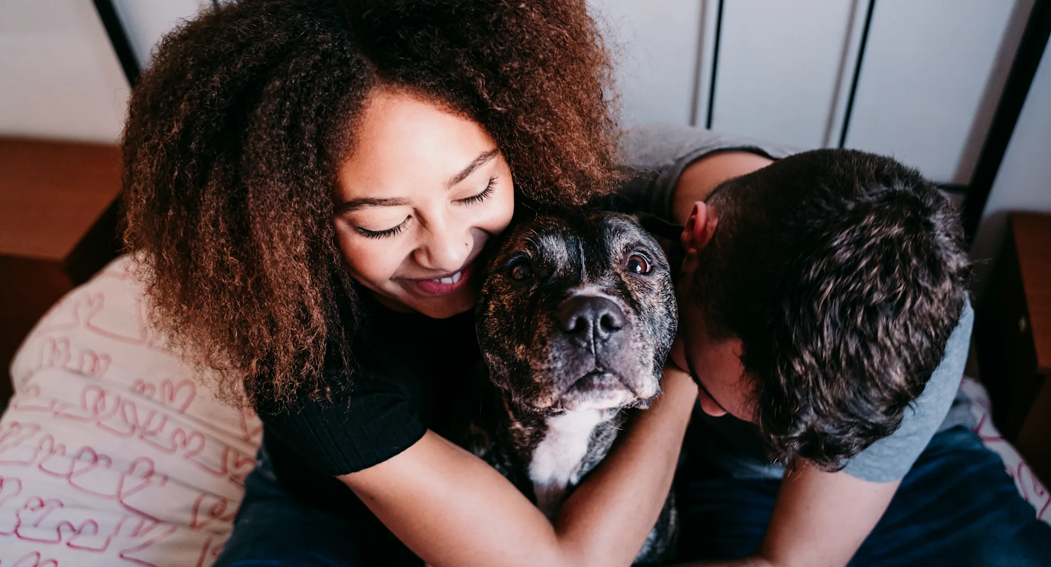 Couple hugging their dog on the bed Couple hugging their dog on the bed