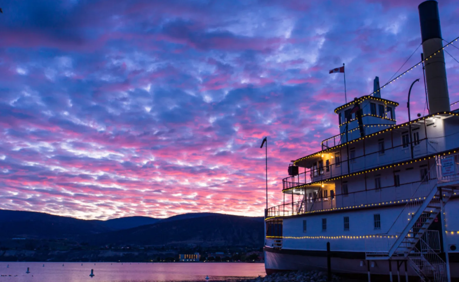 A steam boat next to a colorful sunset in Penticton, BC