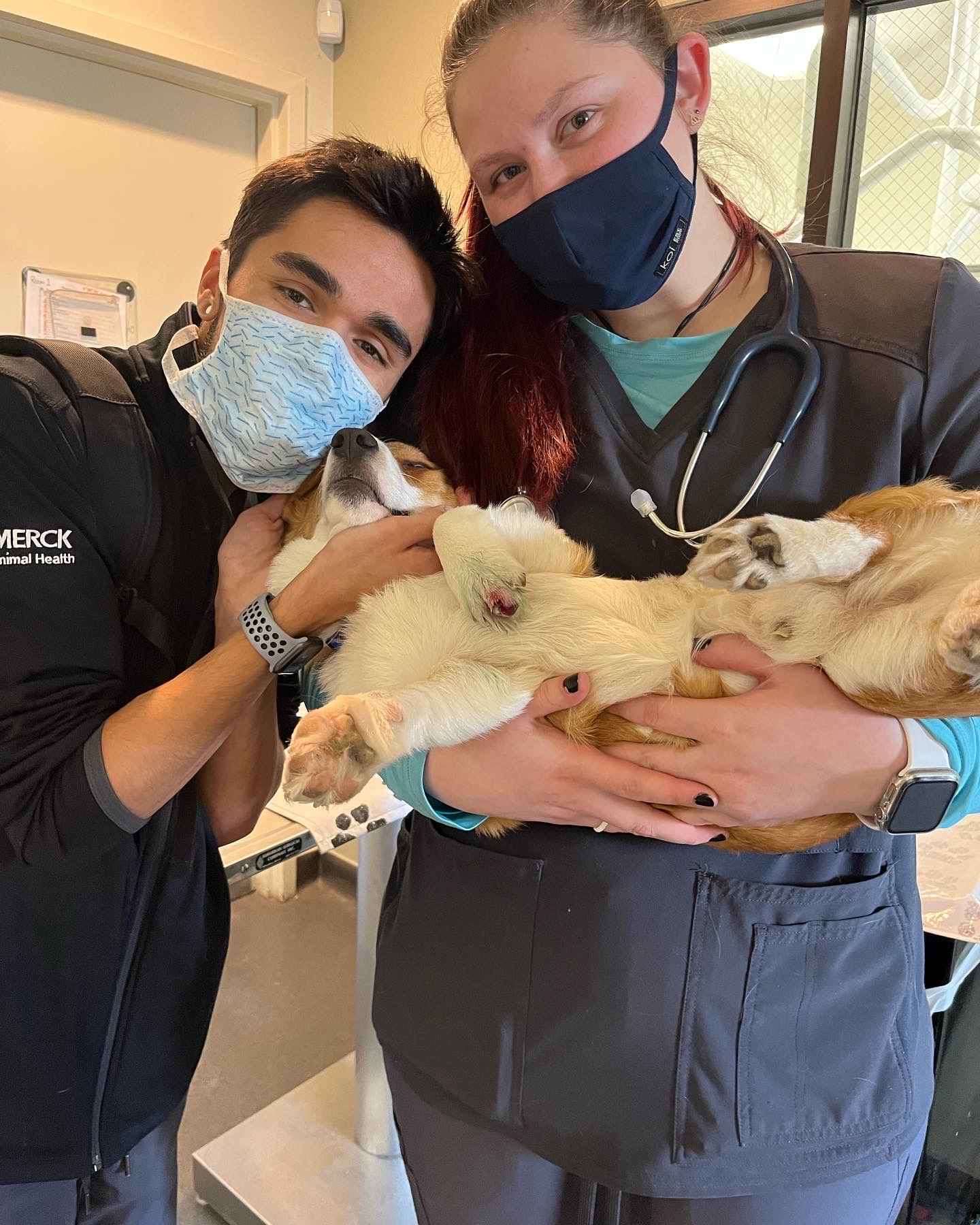 Two staff members holding and posing with a dog.