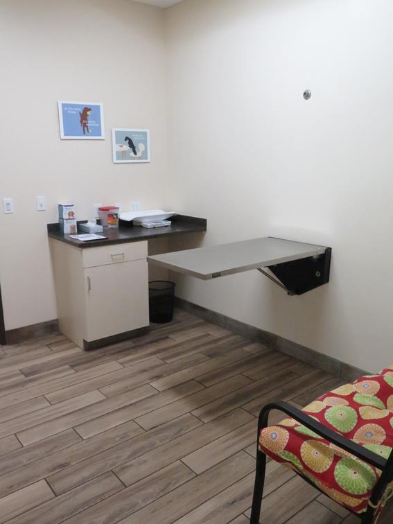 An examination table stuck to the wall is displayed in the middle of an examination room. 