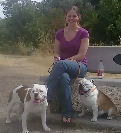 Rebecca R. sitting on a bench with two dogs next to her