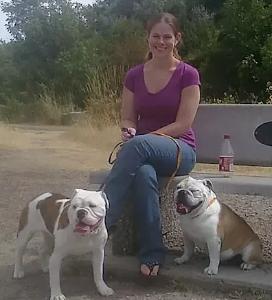 Rebecca R. sitting on a bench with two dogs next to her