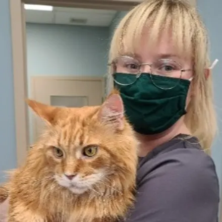 Sydnie wearing a mask holding a large red cat
