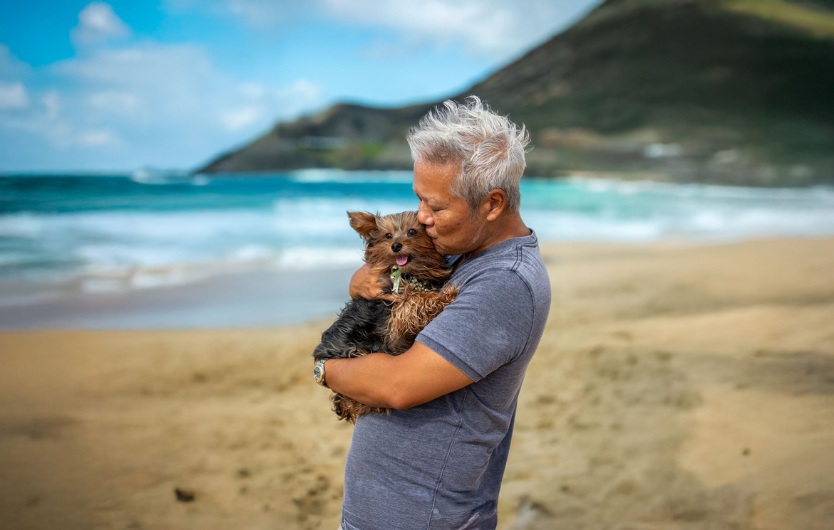 Man hugging yorkie on beach