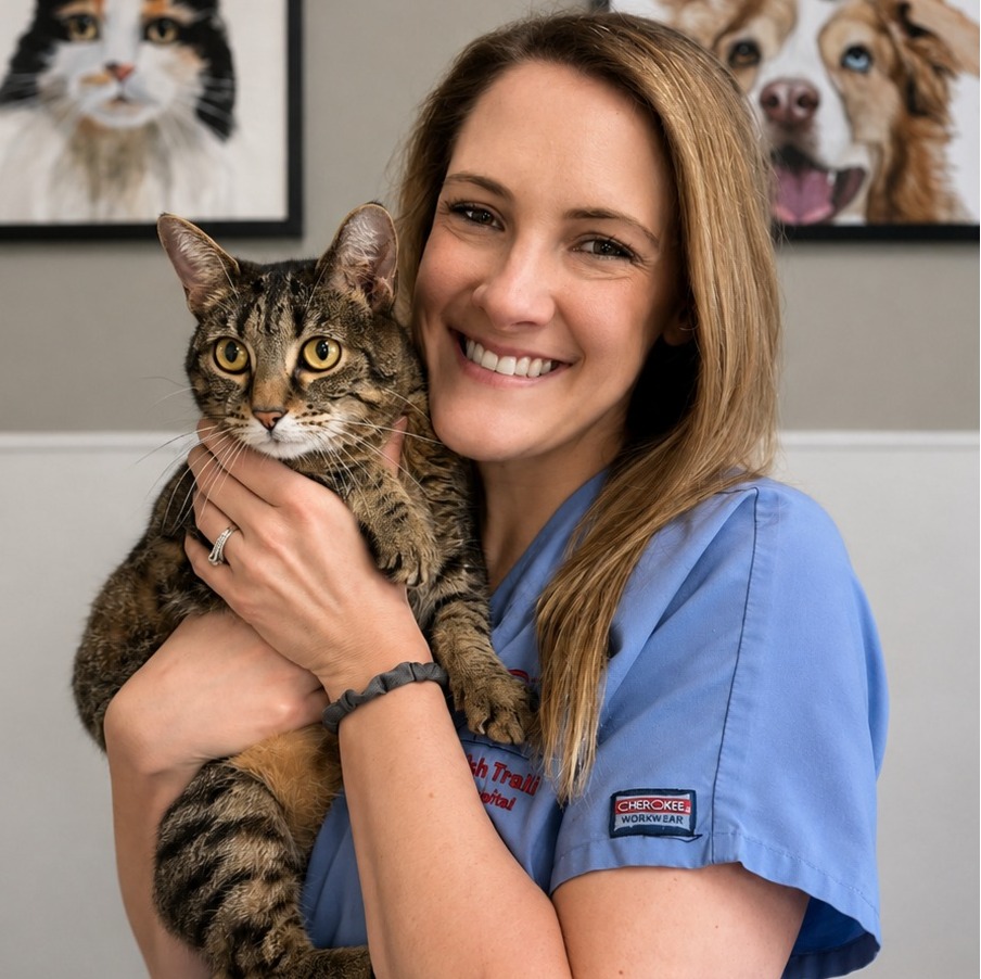 Lindsay C.'s staff photo from Spanish Trail Animal Hospital where she is outside in the front yard holding a fluffy brown dog in her arms.
