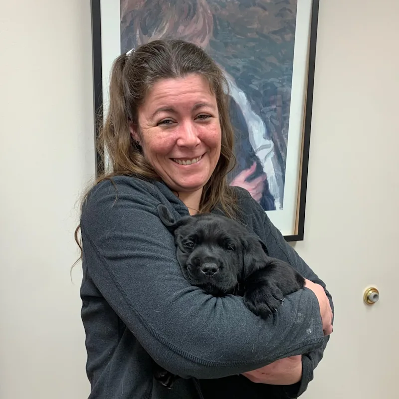 Holly smiling, holding a black puppy Holly smiling, holding a black puppy