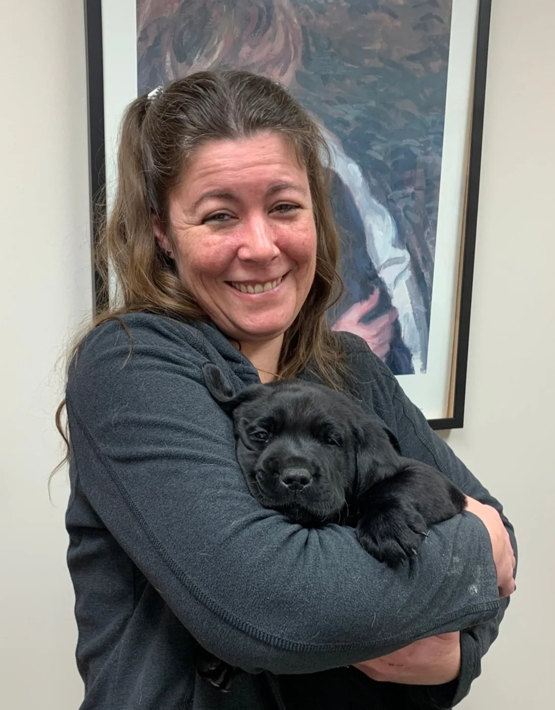 Holly smiling, holding a black puppy Holly smiling, holding a black puppy
