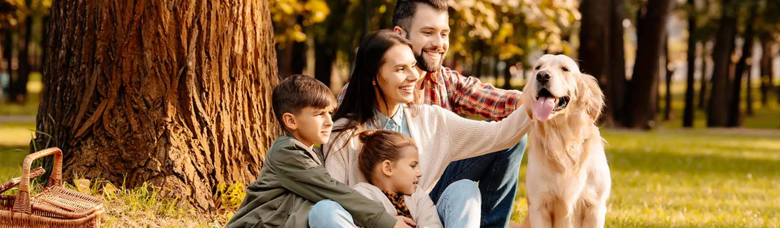 family sitting in the grass with their dog at the park