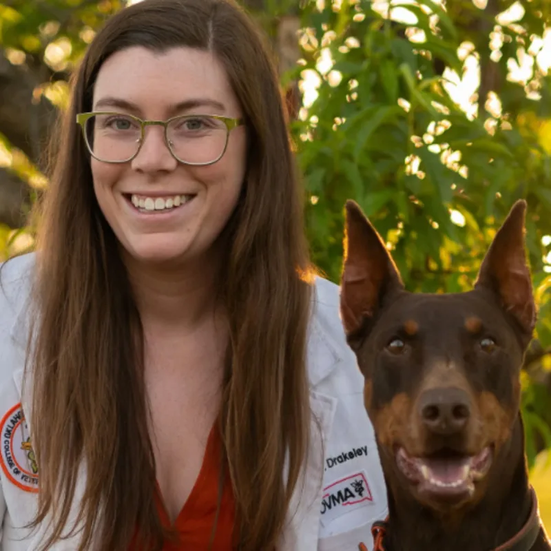 Dr. Molly Drakeley smiling next to a Doberman Dr. Molly Drakeley smiling next to a Doberman